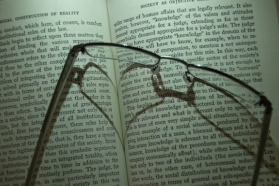 Glasses resting atop an open copy of The Social Construction of Reality